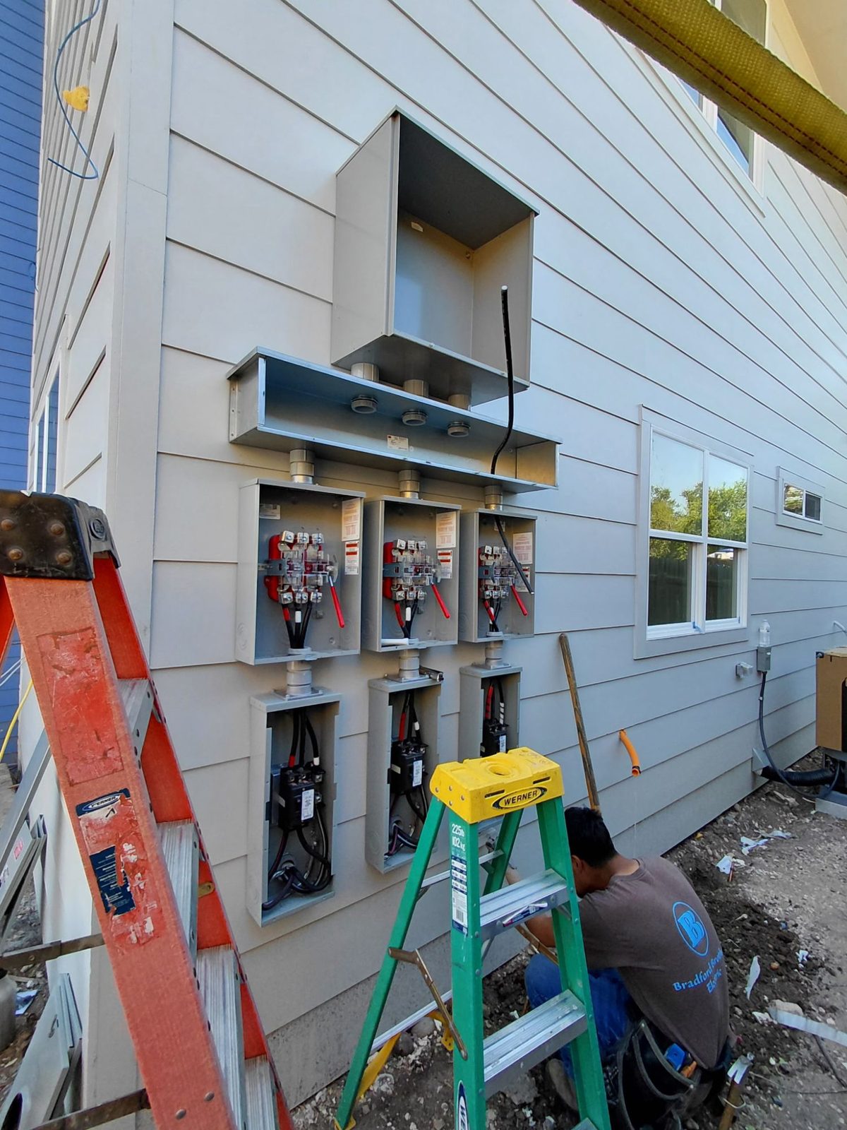 Three meter sockets and disconnects being installed on the exterior of a multi-family building